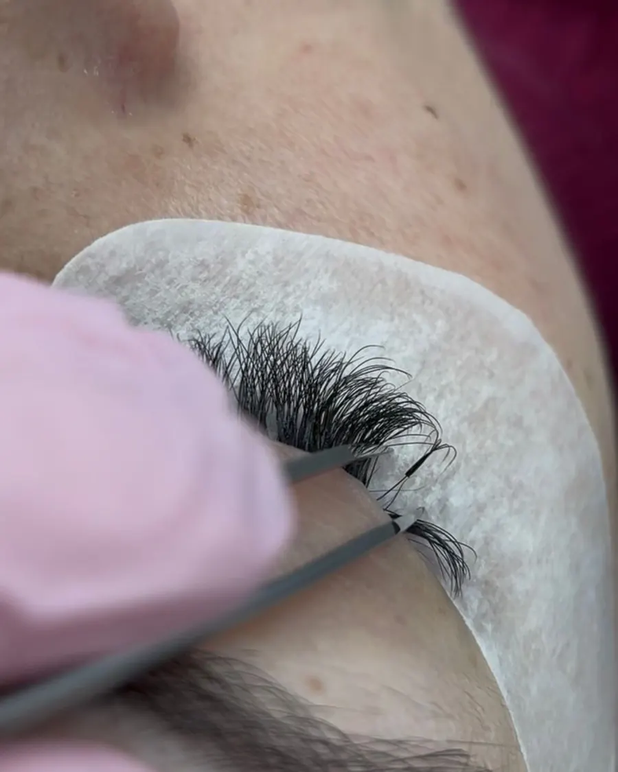 Pinça retirando um fio de extensão da linha dos cílios durante uma manutenção no Studio Crystal Lashes